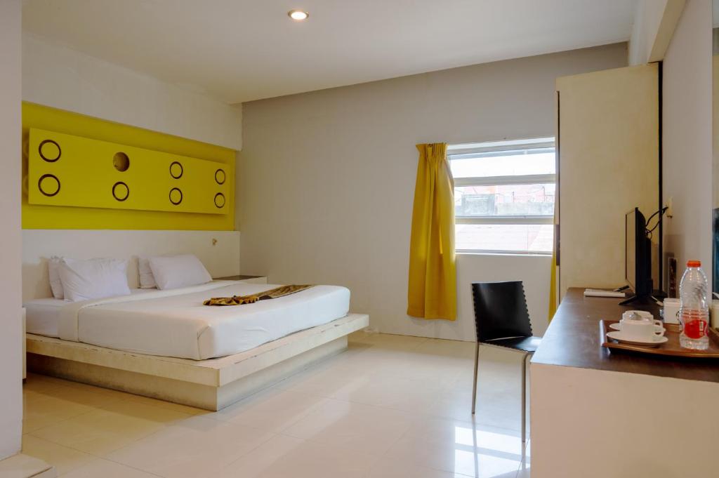 a bedroom with a white bed and a yellow wall at Tripletree Majestiq Hotel in Pekanbaru