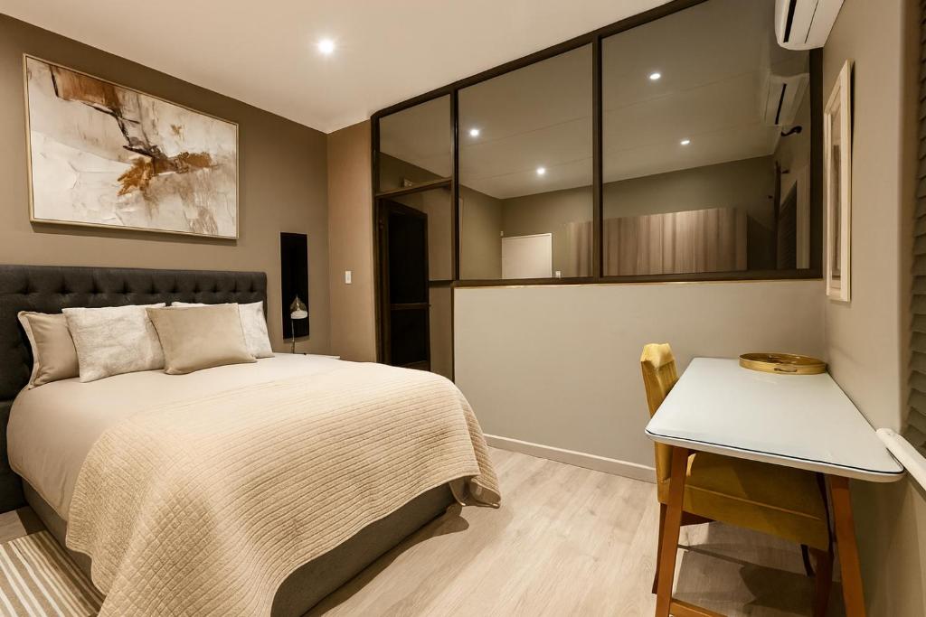 a bedroom with a bed and a table in it at 12a Infinity Guesthouse in Pietermaritzburg