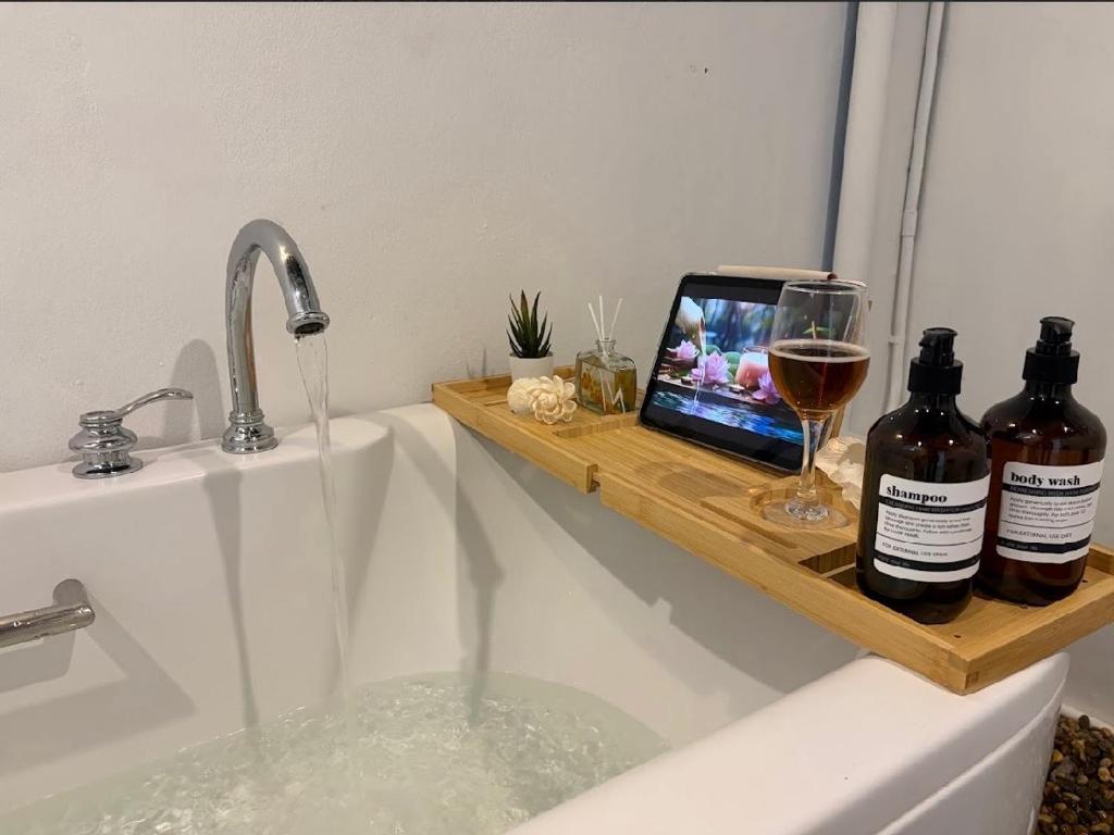 a bath tub with a glass of wine and a tablet at Cozy house hatyai in Sathani Khlong Rian