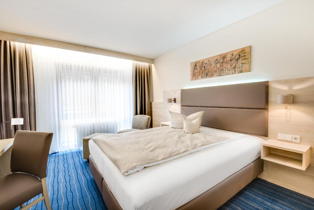 una habitación de hotel con una cama grande y una silla en Business Class Hotel Häckermühle, en Tiefenbronn