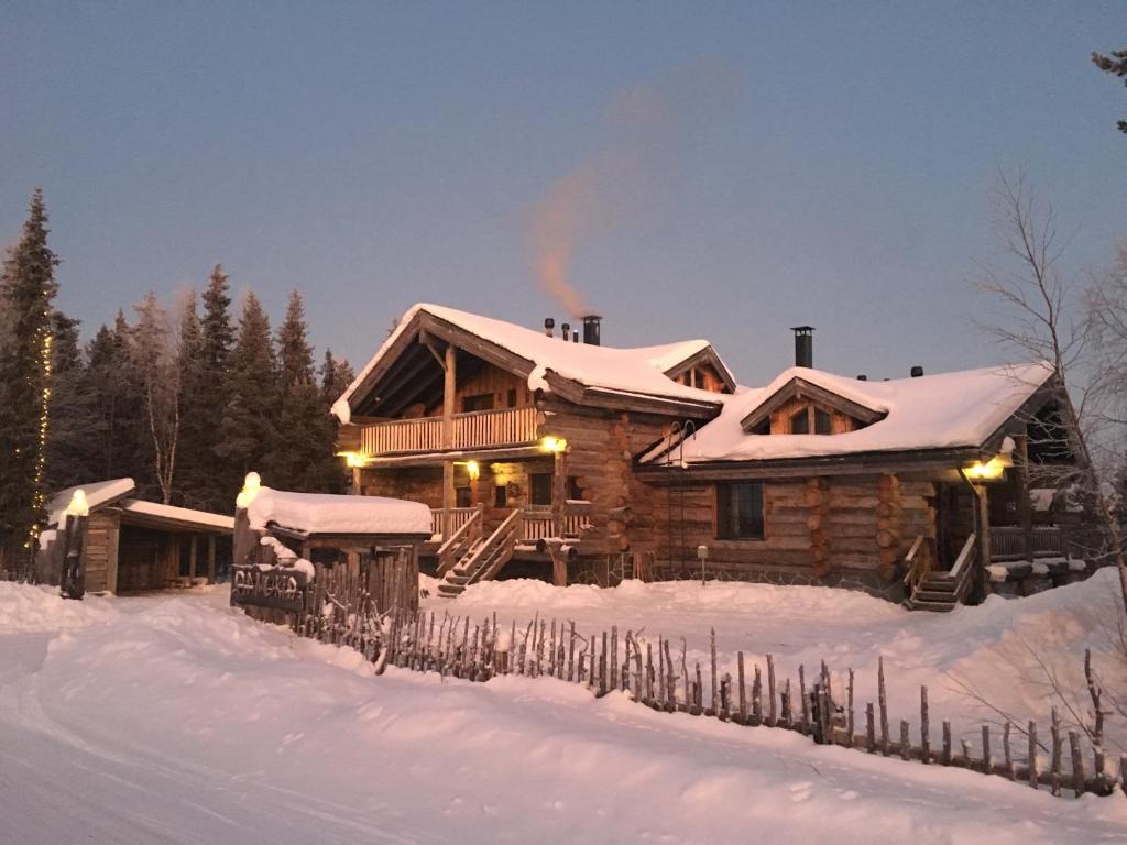 una cabaña de madera en la nieve con nieve en Aamukka A&B, en Levi