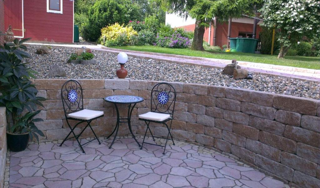 a patio with two chairs and a table against a brick wall at Holiday Home Mergenhofweg in Immenhausen