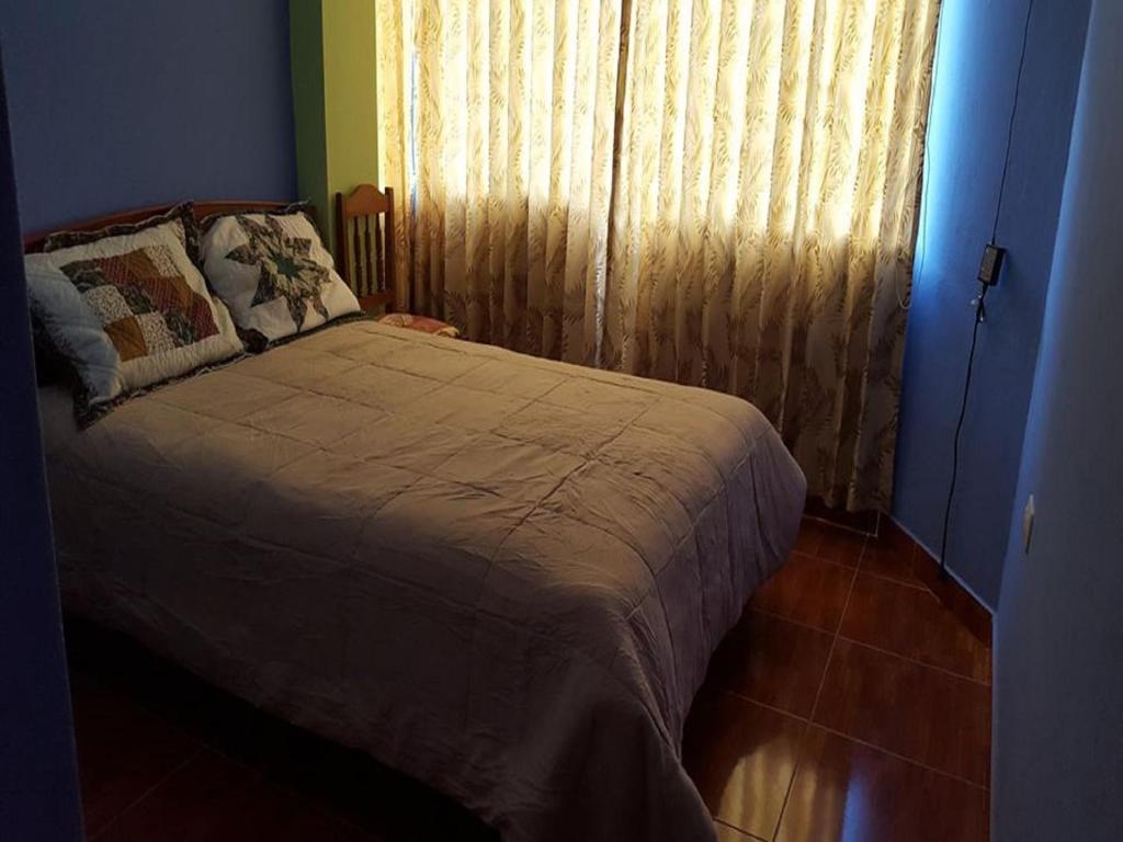 a bedroom with a bed and a window with curtains at Hostal Arcangel in Abancay