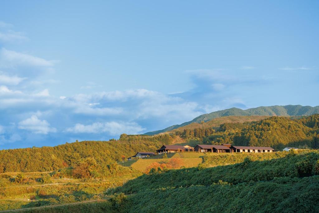 a house on a hill with mountains in the background at AUBERGE de SENVIE in Sakurai