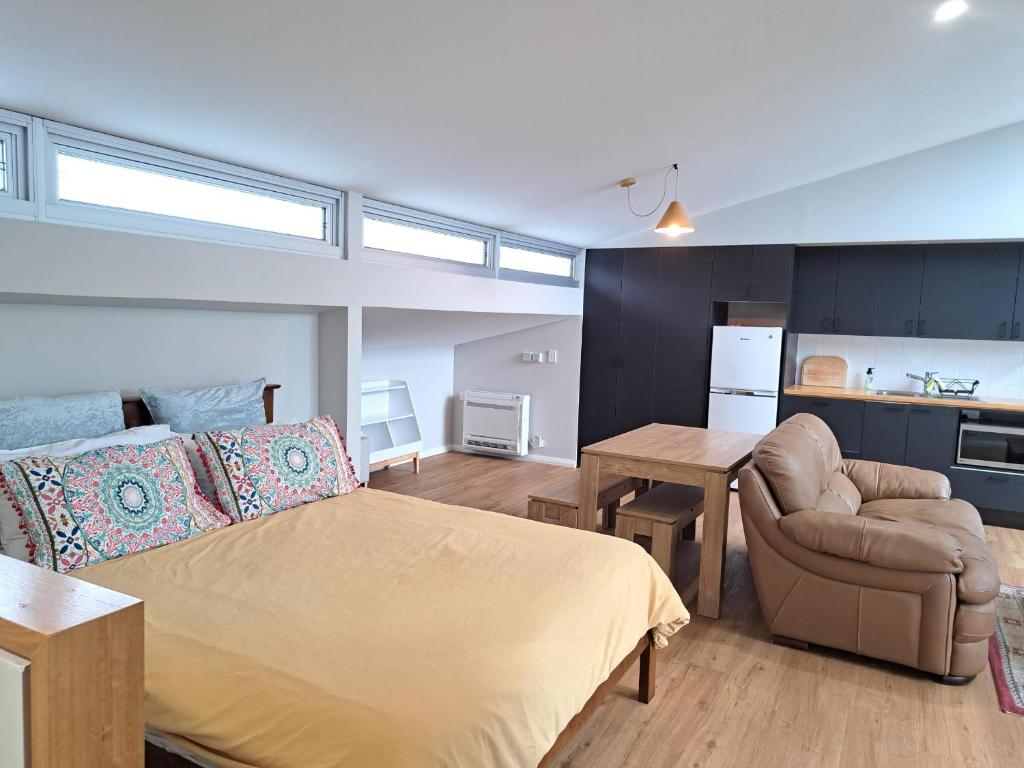 a bedroom with a bed and a couch and a table at Studio Apartment close to the CBD in Unley