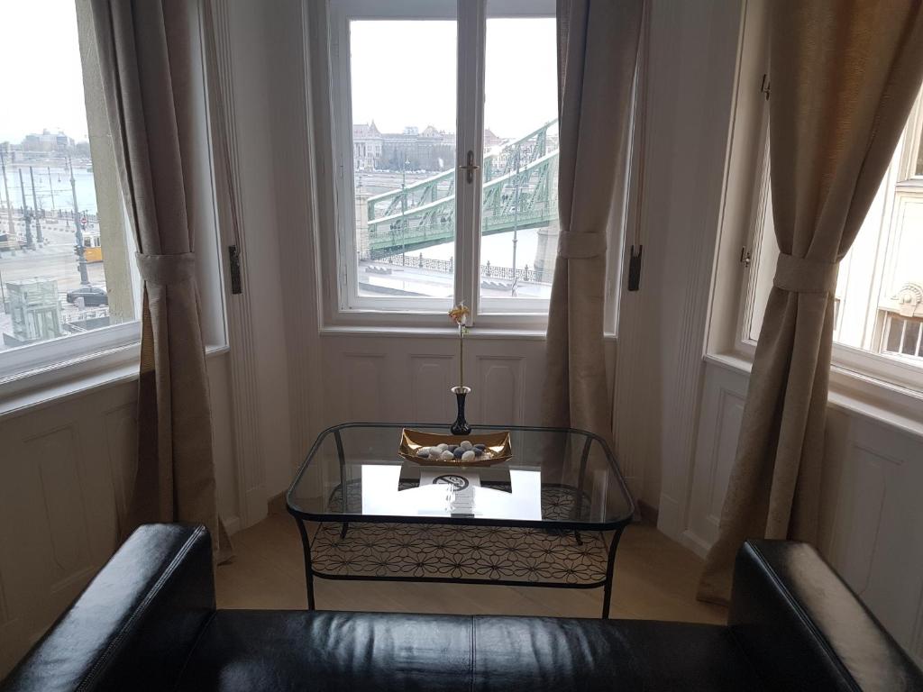 ブダペストにあるバタフライ ホーム ドナウのテーブルと椅子2脚、窓2つが備わる客室です。