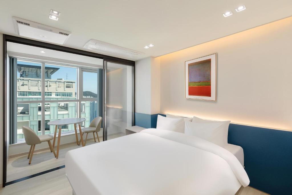 a hotel room with a bed and a balcony at 센텀 뉴시즈 호텔 in Millak-tong