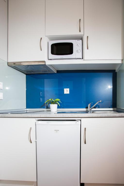 a kitchen with white cabinets and a microwave at Chic Studios in Parede