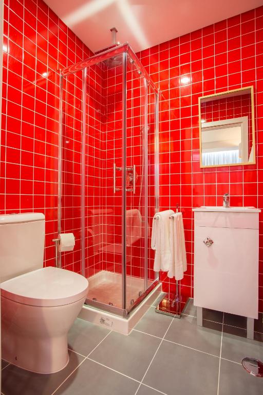 a red tiled bathroom with a toilet and a shower at Chic Studios in Parede