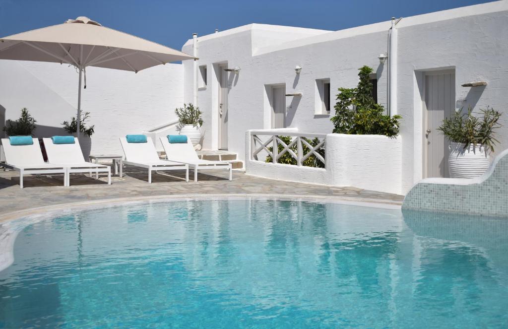 a swimming pool with chairs and an umbrella at Kanale's Rooms & Suites in Naousa