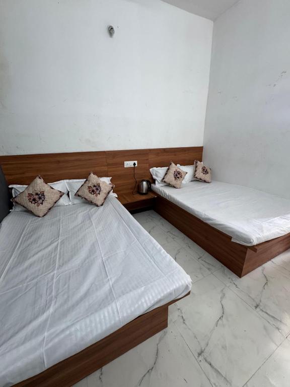 two beds in a room with white walls at Gajanand Homestay in Ujjain