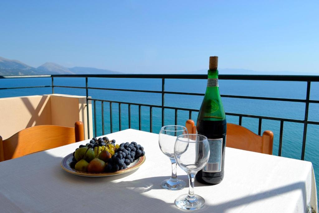 a table with a bottle of wine and a bowl of fruit at Villa Panorma in Qeparo