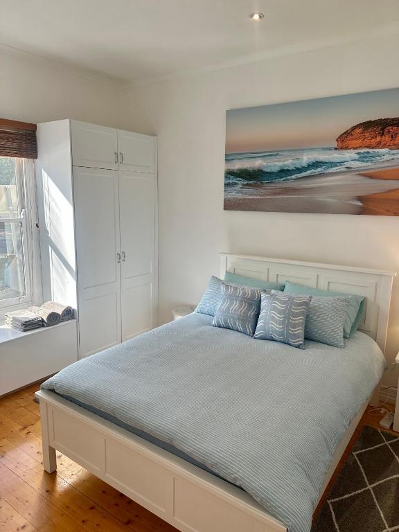 a bedroom with a bed with a painting on the wall at Botanical Gardens City Cottage in Geelong