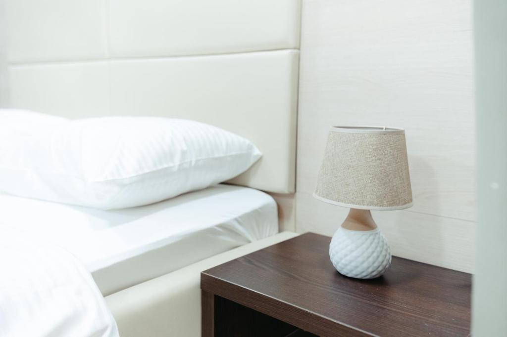 a lamp on a wooden table next to a bed at Koncept RK in Banja Luka