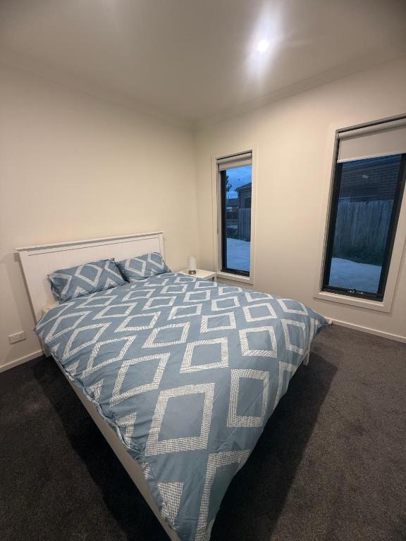 a bedroom with a large bed and two windows at Peaceful Room in Wyndham Vale for Stay in Wyndham Vale