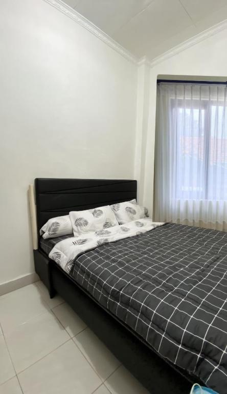 a bedroom with a black bed with a window at Rama Shinta Guesthouse & Coffee Yogyakarta in Yogyakarta