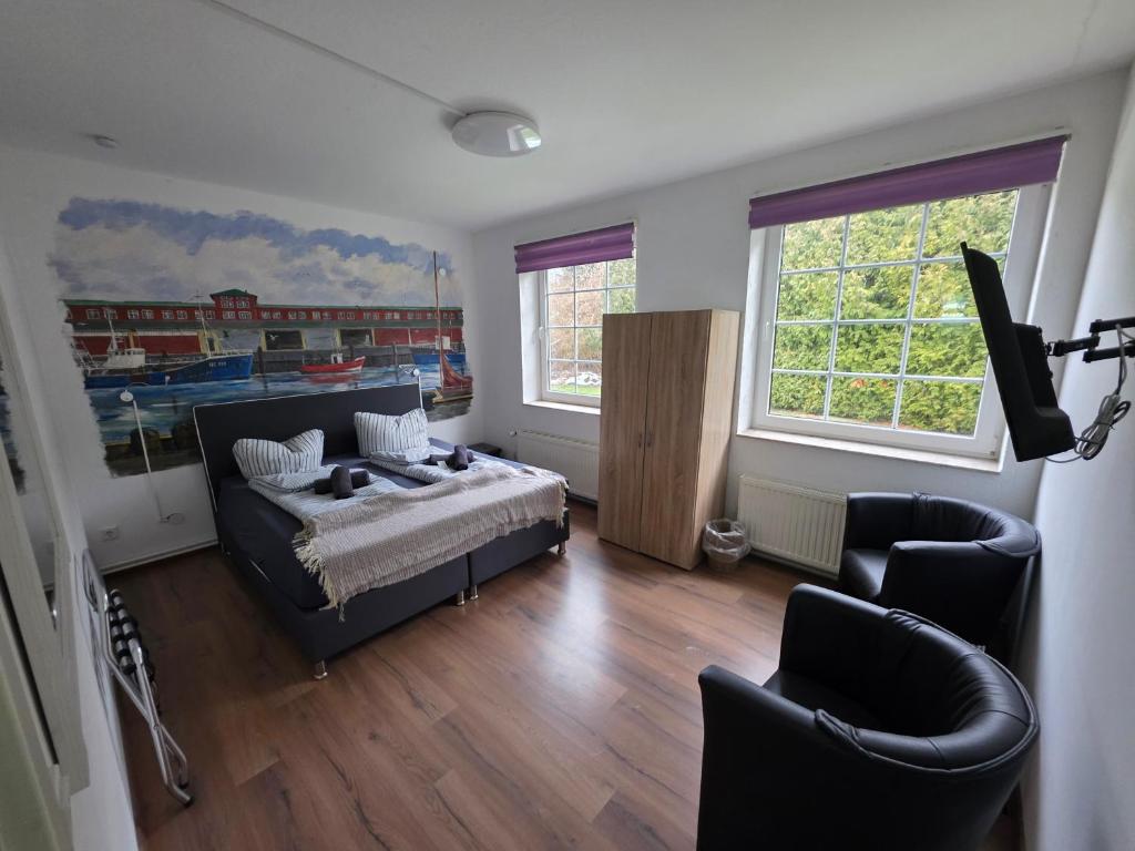 a bedroom with a bed and two chairs and two windows at Gästehaus Strandbake in Cuxhaven