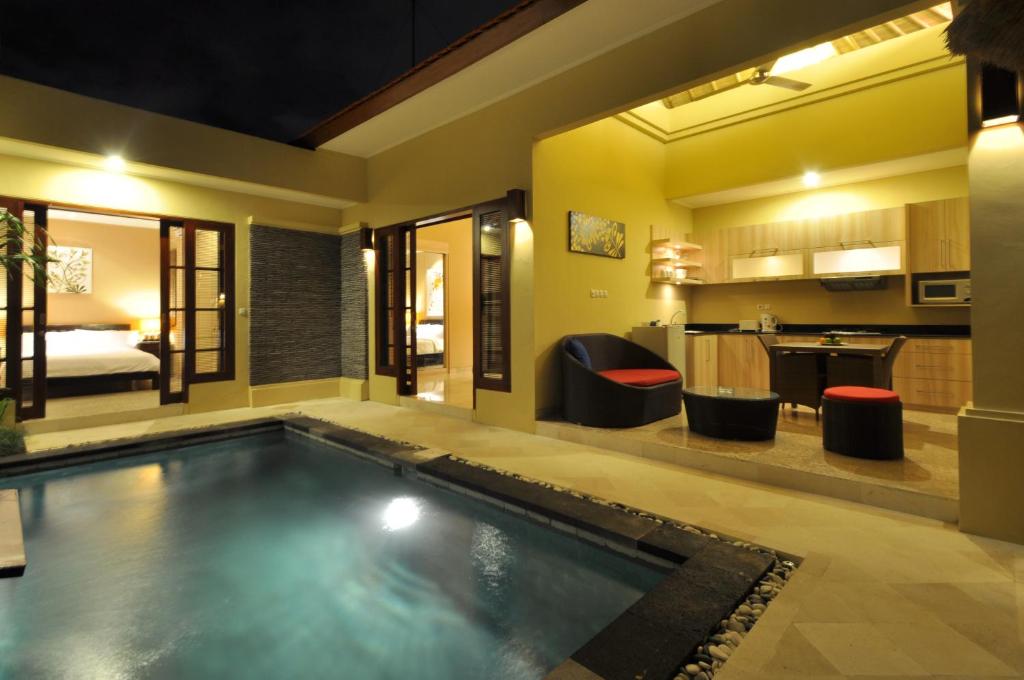 a hotel room with a swimming pool and a bedroom at The Jas Villas in Seminyak