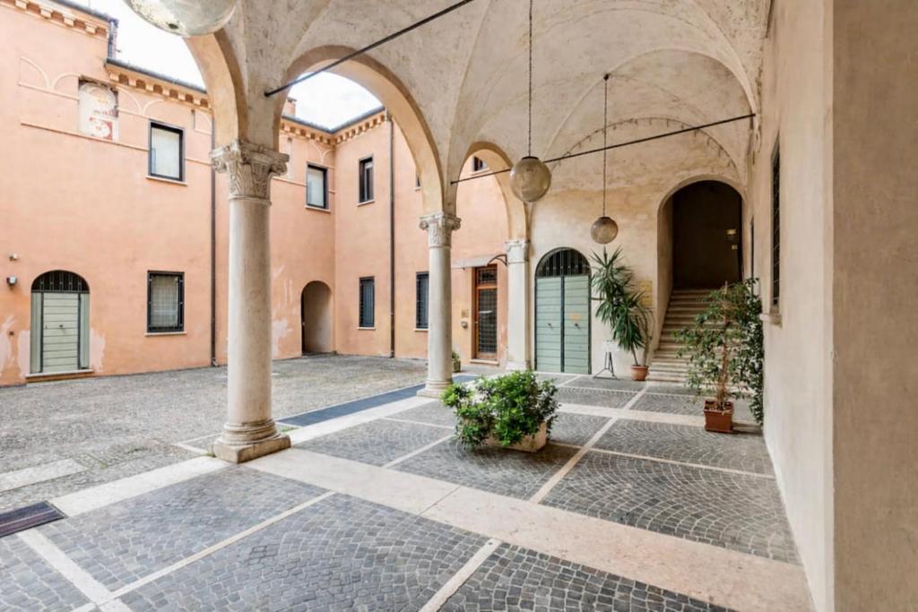 an empty courtyard with arches and plants in a building at Residenza Palazzo Petrozzani in Mantova