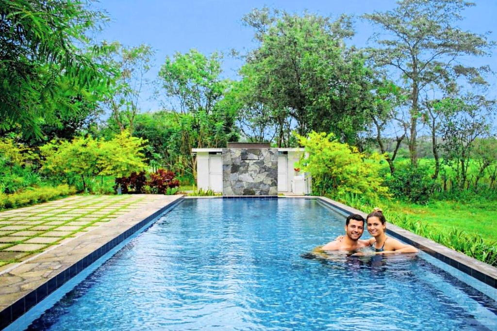 a man and woman swimming in a swimming pool at Kadulla Resort in Habarana