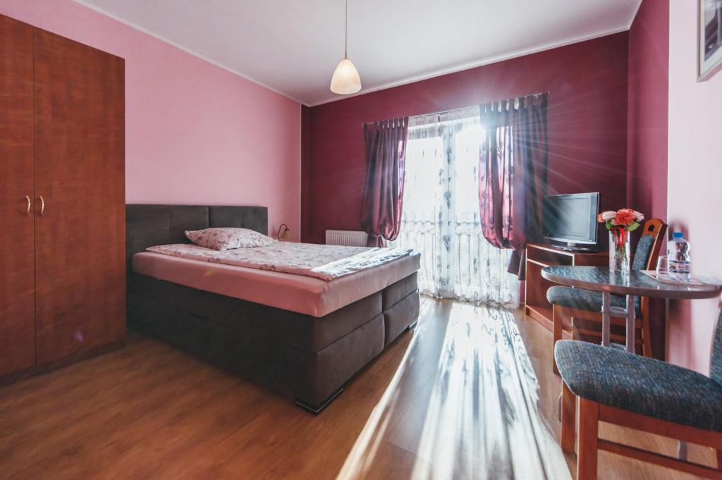 een slaapkamer met een bed, een tafel en een raam bij Willa Promyk in Gdańsk