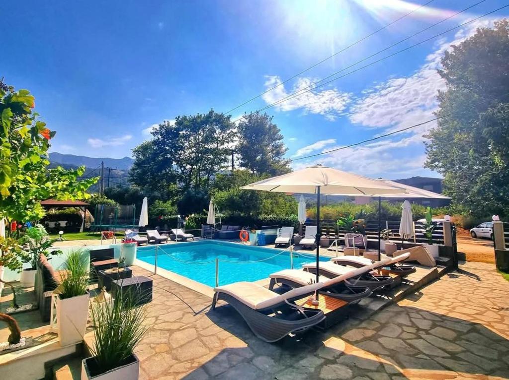 a swimming pool with lounge chairs and an umbrella at Villa Valeria Thassos in Limenas