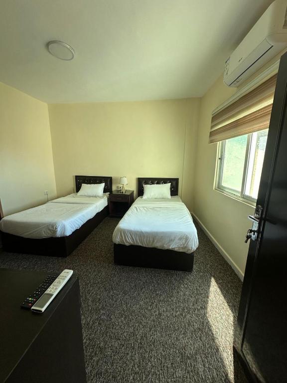 a bedroom with two beds and a desk and a window at Sultan Palace Apartments in Wadi Musa