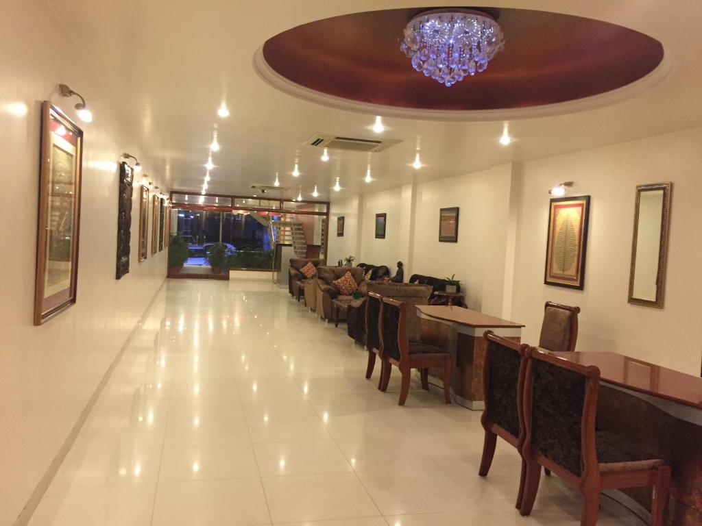 a restaurant with tables and chairs and a chandelier at Hotel Sarthak in Bhopal
