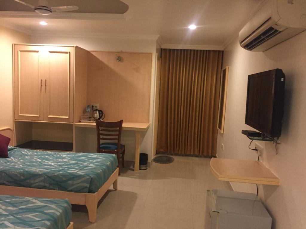 a room with a bed and a desk and a television at Hotel Sarthak in Bhopal
