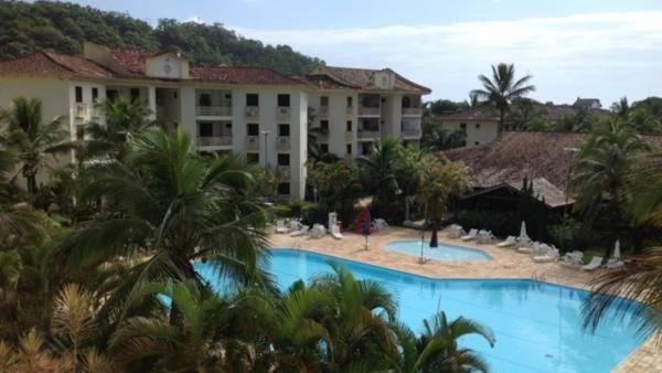 a large hotel with a swimming pool and palm trees at Condomínio Clube Wembley Tennis in Ubatuba