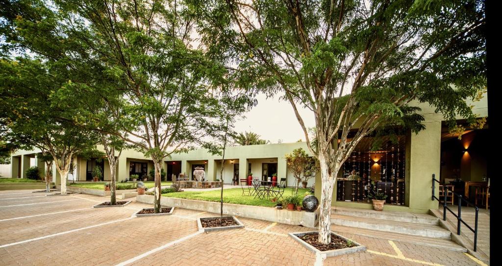 a group of trees in front of a building at Hadassa Guest House in Otjiwarongo