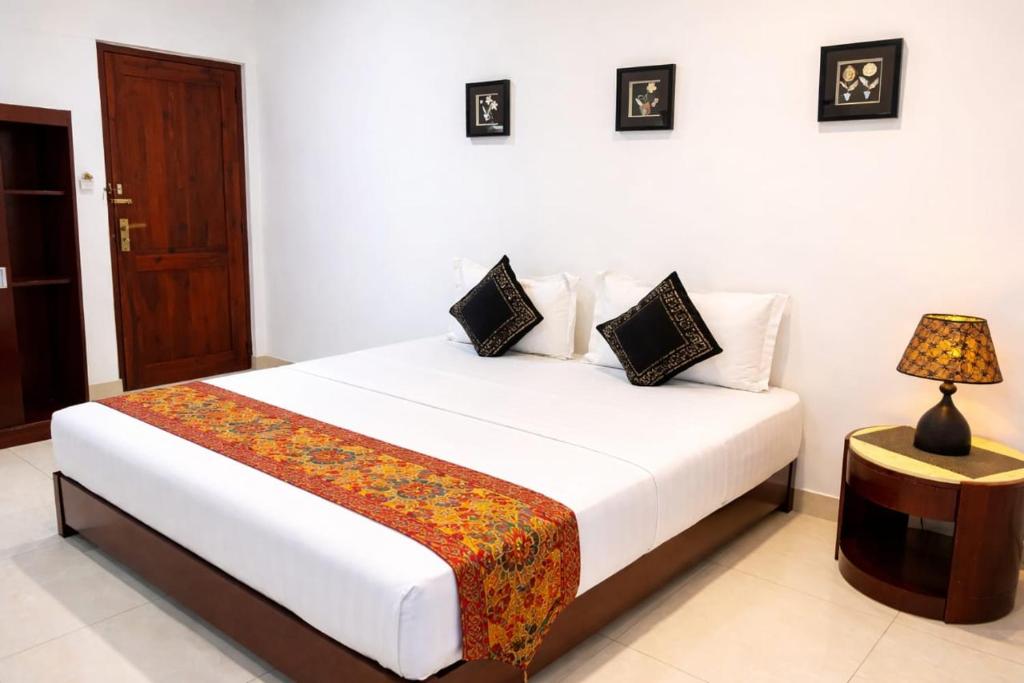 a bedroom with a bed with a table and a lamp at The Residence Dambulla in Dambulla