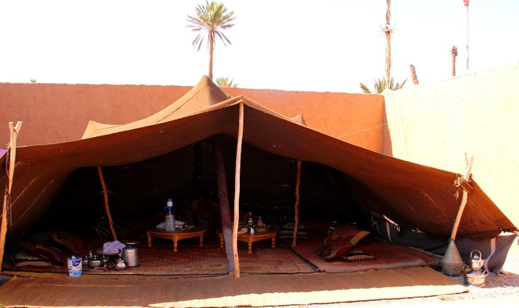 a large brown tent with a table and palm trees at Tarmguist in Tighmert
