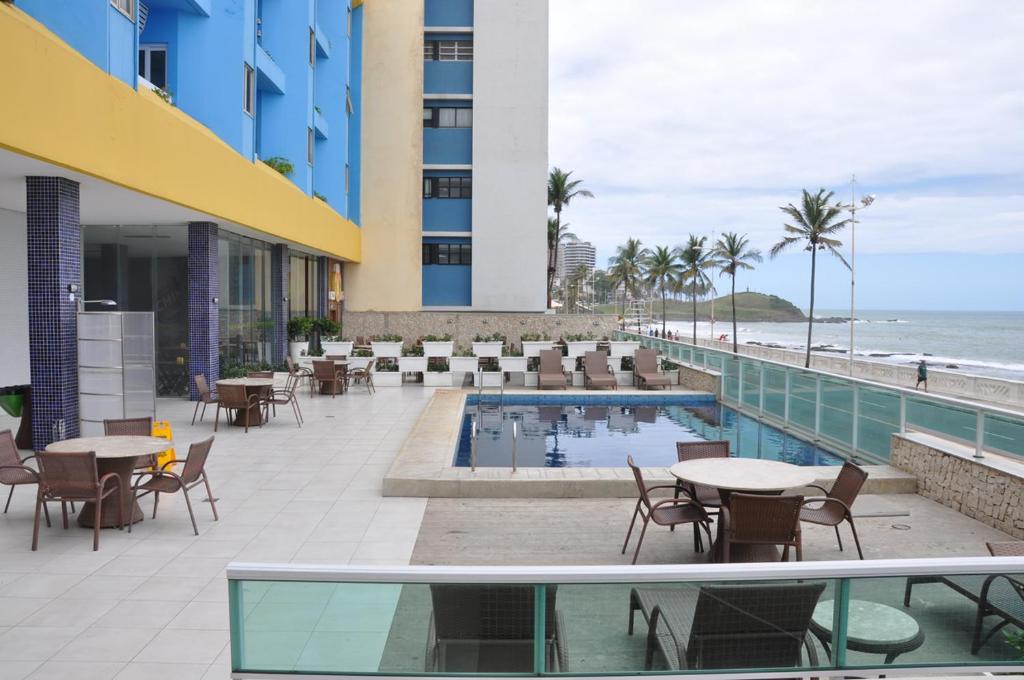 a hotel patio with tables and chairs and the beach at Bahia Flat ap 206 in Salvador