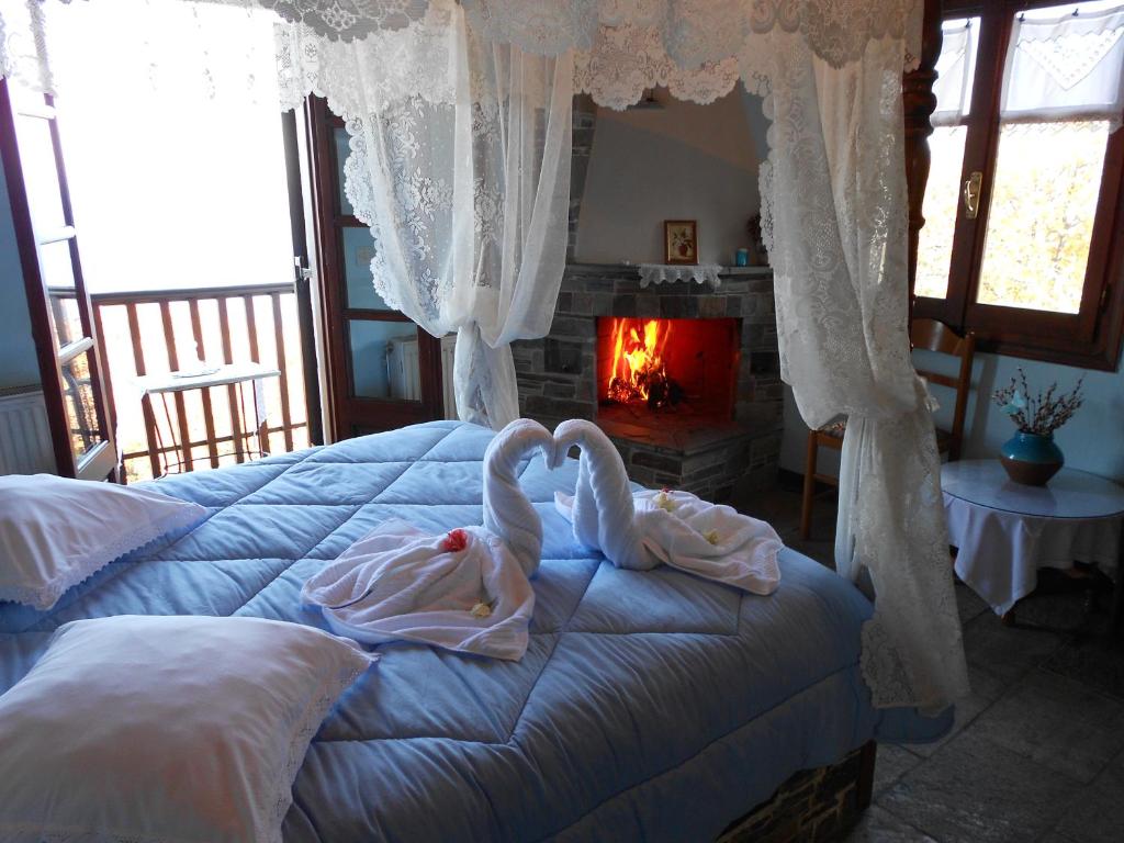 two swans sitting on a bed in a bedroom with a fireplace at Diogenis Hotel in Tsagarada
