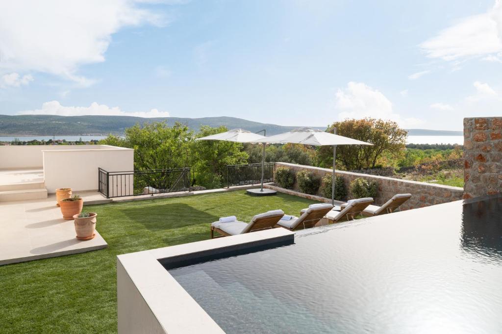 a backyard with a swimming pool and chairs and an umbrella at Casa Sorelle secluded villa with breathtaking pool in Seline