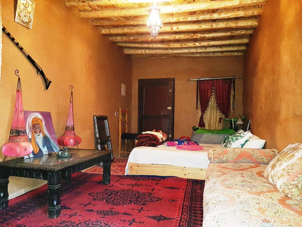 a bedroom with two beds and a table and a couch at Tarmguist in Tighmert