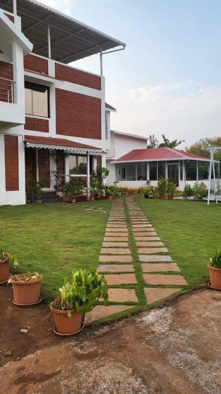 a building with a walkway in front of a yard at Nisarg Forever Resort in Jāmb
