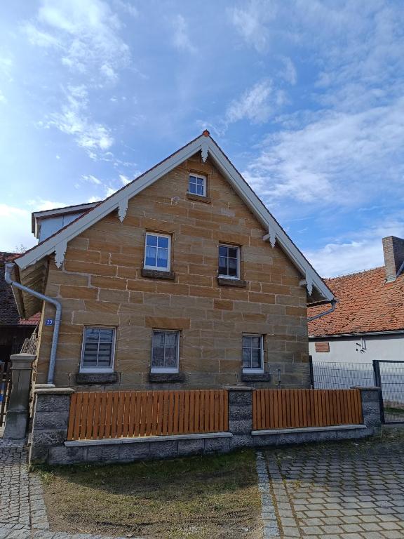 a large wooden house with windows on a brick yard at Ferienhaus Mitteldachstetten, ruhige Lage, kostenlos parken, WLAN free in Oberdachstetten