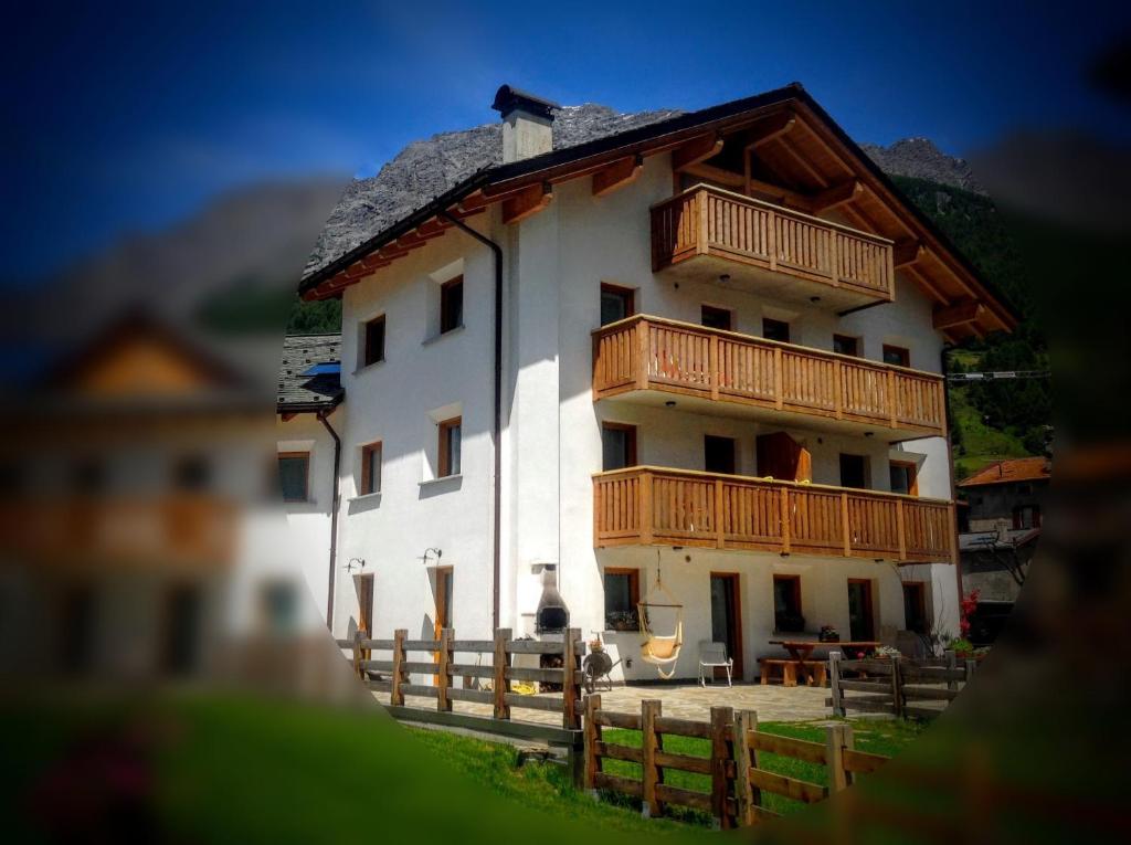 un grande edificio bianco con balconi in legno di Casa Betty a Bormio