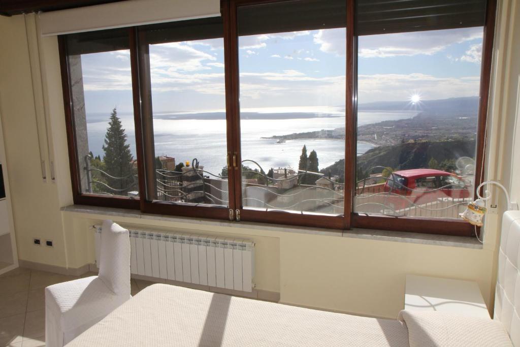 um quarto com uma grande janela com vista para o oceano em Sicula em Taormina