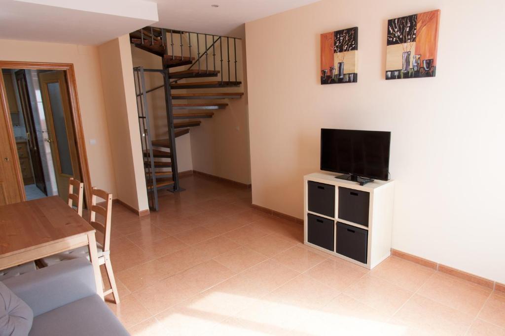 sala de estar con TV y mesa de comedor en Apartamentos Río Guadalaviar, en Albarracín