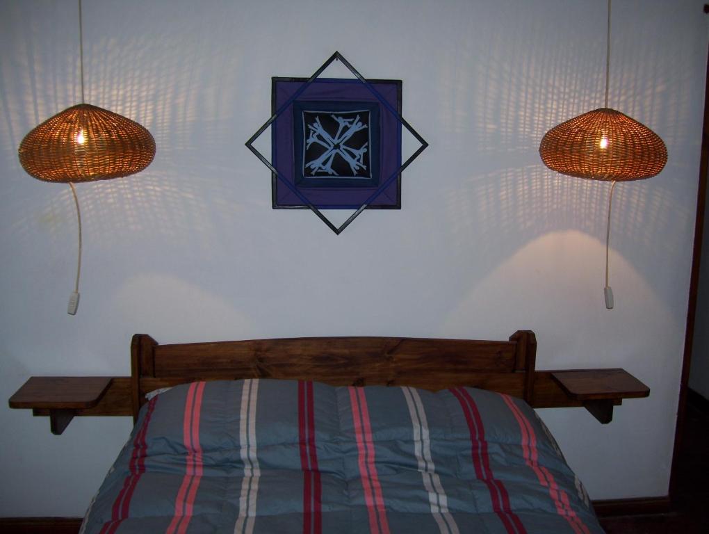 a bedroom with a bed with two lights and a clock on the wall at Casa Abedules de los Andes in San Martín de los Andes