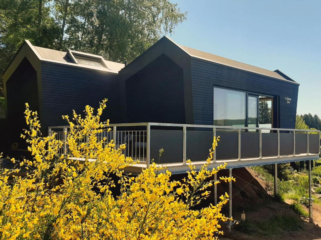 a black house with a deck and yellow flowers at Rausblick Cabin in Bruchweiler-Bärenbach