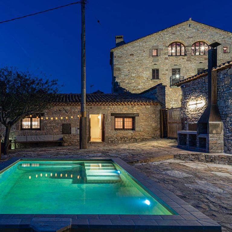 a swimming pool in front of a stone house at Casatona in San Mateo de Bages