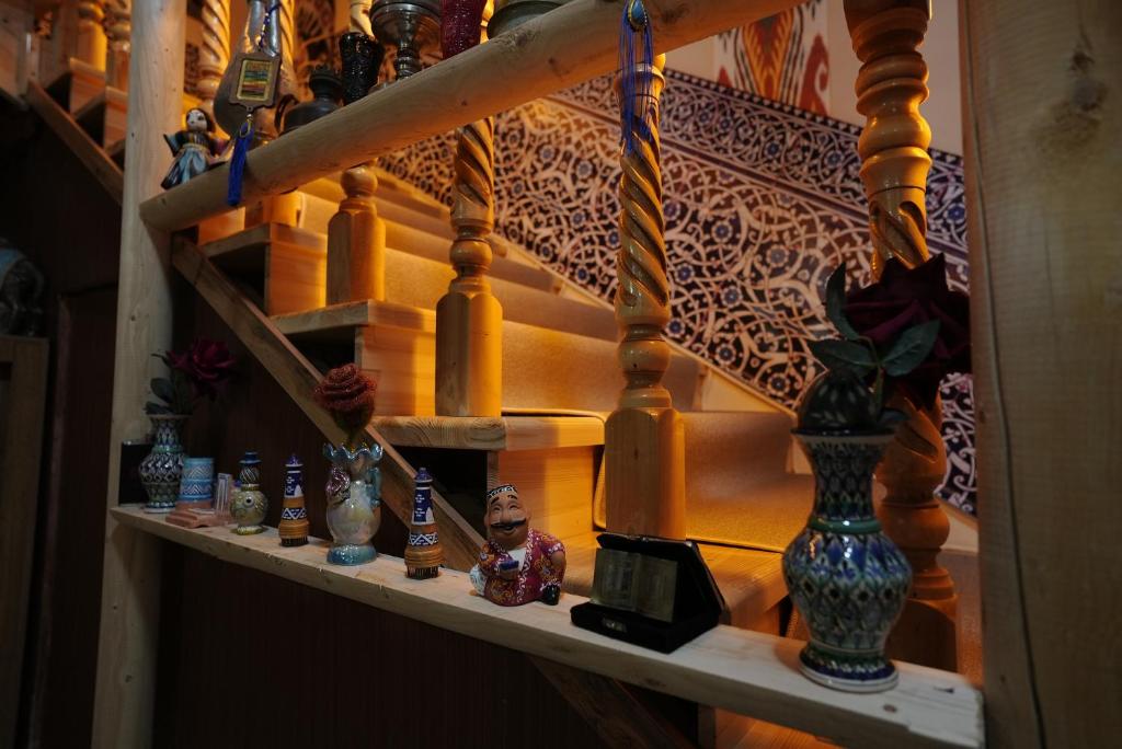 a shelf with vases on it next to a staircase at Rasulboy Guest House in Khiva