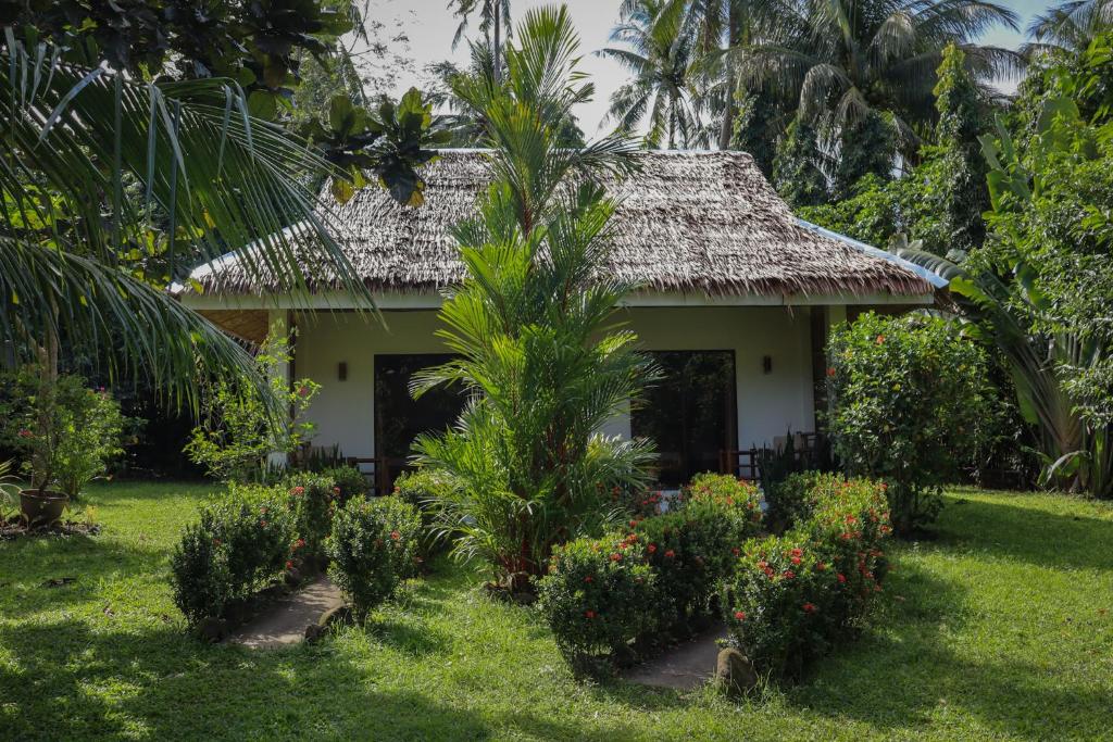 a small house with a palm tree in the yard at Happy Coconut Camiguin in Mambajao