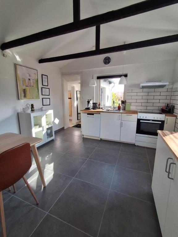 a large kitchen with white cabinets and a table at Strandens Apartment in Ishøj
