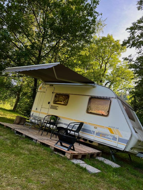 a caravan parked in a field with a table and chairs at Karavan Pod Lipami in Dolní Bečva