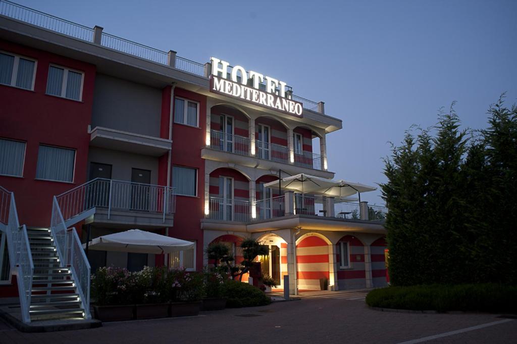 un bâtiment rouge avec un panneau indiquant l'hôtel Midland dans l'établissement Hotel Mediterraneo, à Villa Cortese